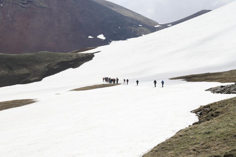 Group of hikers traversing snowy mountain landscape on a bright day.